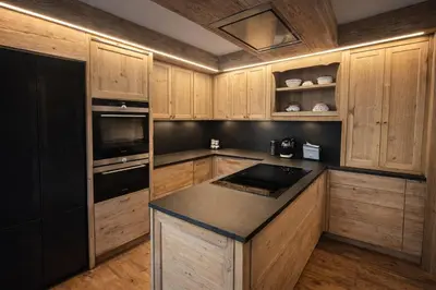 a kitchen with wooden cabinets and a black appliance at Ca Dei Nani - Exclusive stay with sauna in Cortina dʼAmpezzo