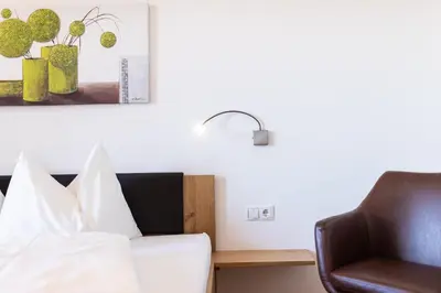 a hotel room with a bed and a chair at Appartements Weisshauserhof in Appiano sulla Strada del Vino