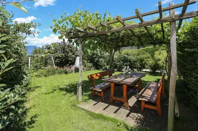 a wooden table and chairs under a wooden pergola at Appartements Weisshauserhof in Appiano sulla Strada del Vino