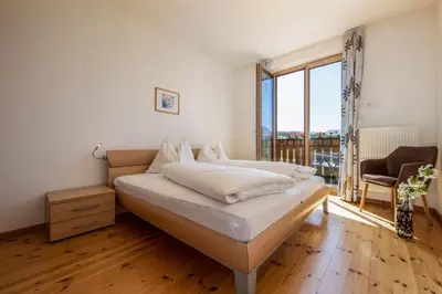 a bedroom with a bed and a large window at Appartements Weisshauserhof in Appiano sulla Strada del Vino