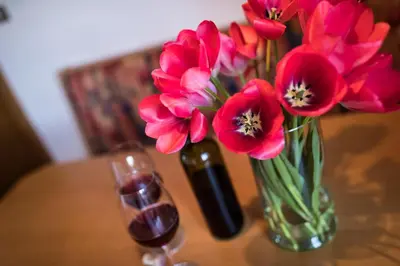 a vase of pink flowers next to a wine glass at Appartements Weisshauserhof in Appiano sulla Strada del Vino