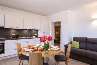 a kitchen and living room with a table with flowers on it at Appartements Weisshauserhof in Appiano sulla Strada del Vino