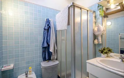 a blue tiled bathroom with a toilet and a sink at Un angolo di comfort nel pieno centro di Cortina in Cortina dʼAmpezzo