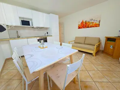 a kitchen and dining room with a table and chairs at Casa Iole - Alpine Stay Apartments in Predazzo