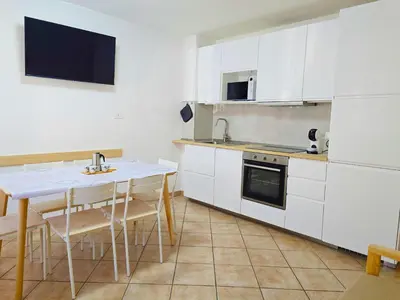 a kitchen with white cabinets and a table with chairs at Casa Iole - Alpine Stay Apartments in Predazzo