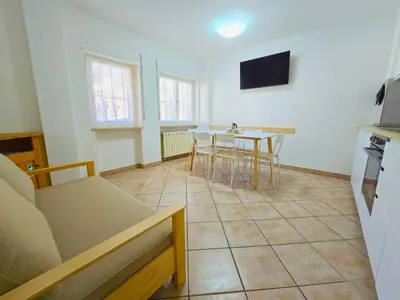 a living room with a table and a tv at Casa Iole - Alpine Stay Apartments in Predazzo