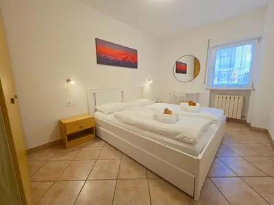 a bedroom with a large white bed and a mirror at Casa Iole - Alpine Stay Apartments in Predazzo
