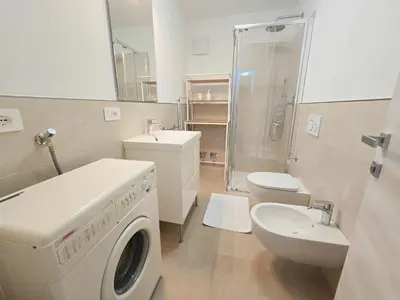 a bathroom with a washing machine and a toilet at Casa Iole - Alpine Stay Apartments in Predazzo