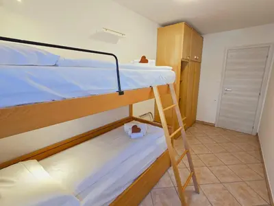 a bunk bed room with two bunk beds and a ladder at Casa Iole - Alpine Stay Apartments in Predazzo