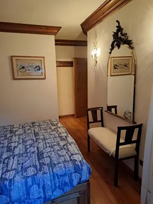 a bedroom with a bed and a chair at Luminoso e ampio appartamento con vista sulle Dolomiti e Tofane in Cortina dʼAmpezzo