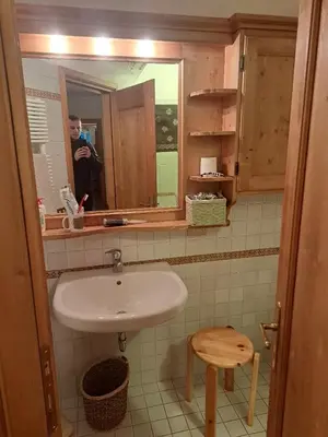 a man taking a picture of a sink in a bathroom at Luminoso e ampio appartamento con vista sulle Dolomiti e Tofane in Cortina dʼAmpezzo
