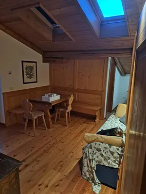 a room with a bed and a table and chairs at Luminoso e ampio appartamento con vista sulle Dolomiti e Tofane in Cortina dʼAmpezzo