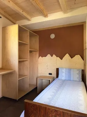 a bedroom with a bed with a wooden headboard and shelves at Appartamento LITEGOSA 2 in Panchia