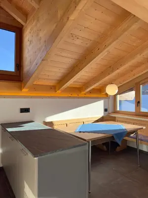 a kitchen with a table in a room with wooden ceilings at Appartamento LITEGOSA 2 in Panchia