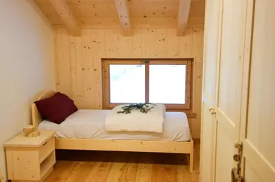 a small bedroom with a bed and a window at Malga Valmaggiore in Bellamonte
