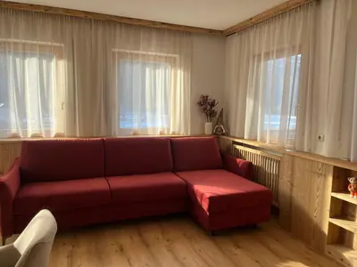 a red couch in a living room with windows at Mountain River Apartment in Chienes