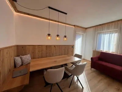 a dining room with a wooden table and a red couch at Mountain River Apartment in Chienes
