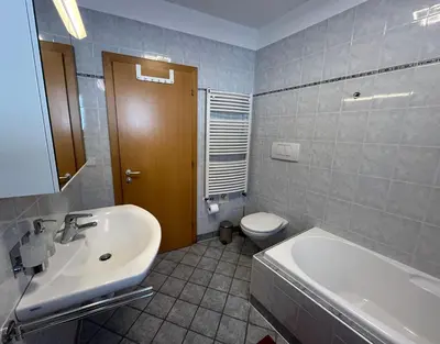 a bathroom with a sink and a tub and a toilet at Mountain River Apartment in Chienes