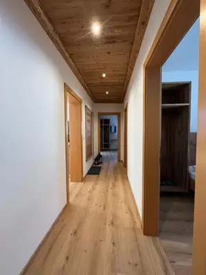 a hallway with white walls and a wooden ceiling at Mountain River Apartment in Chienes