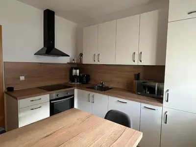 a kitchen with white cabinets and a wooden table at Mountain River Apartment in Chienes