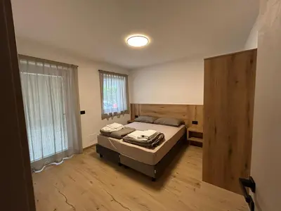 a bedroom with a bed and a large window at FIEMME IN VISTA Apartments in Ziano di Fiemme