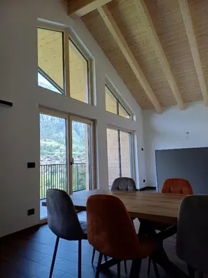 a dining room with a table and chairs and windows at FIEMME IN VISTA Apartments in Ziano di Fiemme