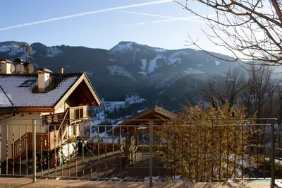 a house with a fence and mountains in the background at Villa Moroseta in Tesero