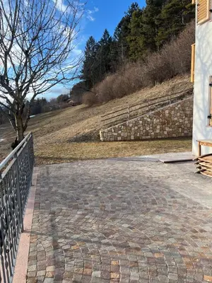 a brick walkway next to a building with a fence at Villa Moroseta in Tesero