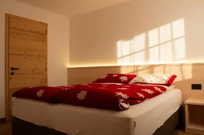 a bed with red and white pillows and a window at Villa Moroseta in Tesero