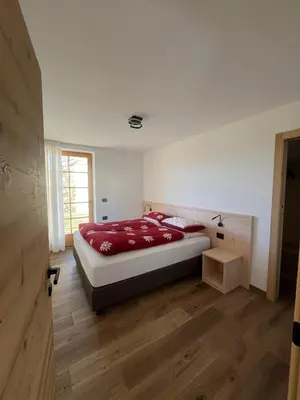 a bedroom with a bed with red sheets and a window at Villa Moroseta in Tesero