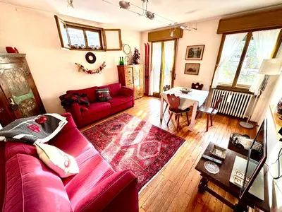 a living room with a red couch and a table at Ca Radiosa - Via Guide Alpine in Cortina dʼAmpezzo