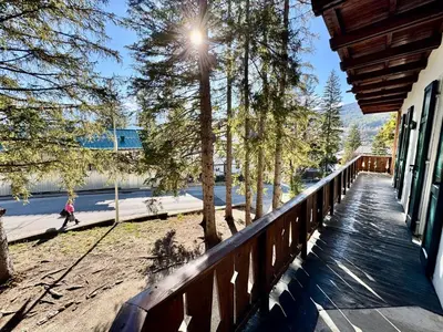 a porch of a house with a woman walking on the sidewalk at Villa Augusta-central apartment in Cortina dʼAmpezzo