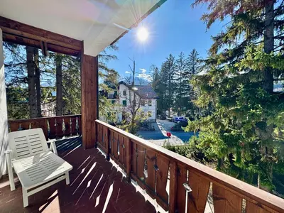 a porch with a white chair and a view of a street at Villa Augusta-central apartment in Cortina dʼAmpezzo