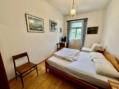 a bedroom with a bed and a chair and a window at Villa Augusta-central apartment in Cortina dʼAmpezzo