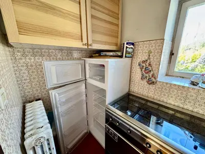 a small kitchen with a white refrigerator and a window at Villa Augusta-central apartment in Cortina dʼAmpezzo