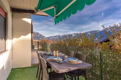 a table on a balcony with a view of mountains at Trilo Ciasa Brìma in Carano