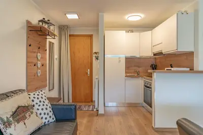 a kitchen with white cabinets and a couch in a room at Trilo Ciasa Brìma in Carano