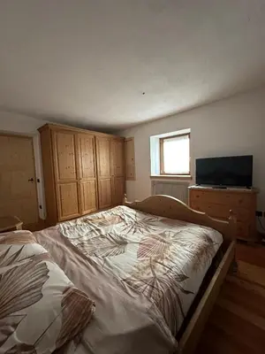 a bedroom with a large bed and a television at Il nido delle cime in Capriana