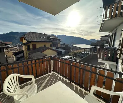 a balcony with two chairs and a view of a city at Il nido delle cime in Capriana