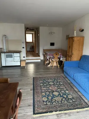 a living room with a blue couch and a table at Il nido delle cime in Capriana