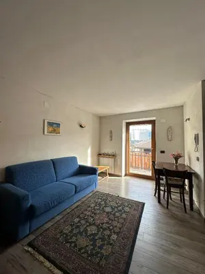 a living room with a blue couch and a table at Il nido delle cime in Capriana