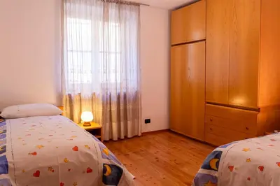 a bedroom with two beds and a dresser and a window at Casa Rita Roen - Ruffrè-Mendola in Ronzone