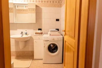 a bathroom with a washing machine and a sink at Casa Rita Roen - Ruffrè-Mendola in Ronzone