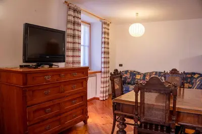 a living room with a tv and a wooden dresser with a wooden table at Casa Rita Roen - Ruffrè-Mendola in Ronzone