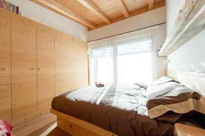 a bedroom with wooden walls and a bed with a window at Awakening in the Dolomites between Pelmo and Antelao in Borca di Cadore