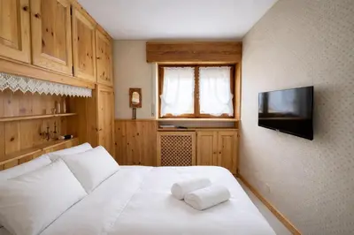 a bedroom with a white bed and a television at Ca La Casetta in Cortina dʼAmpezzo