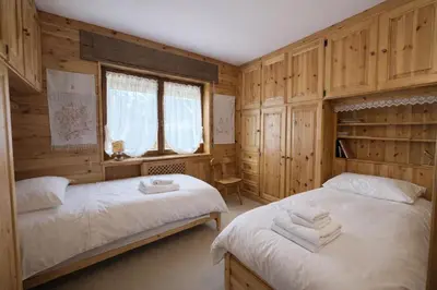 two beds in a room with wooden walls at Ca La Casetta in Cortina dʼAmpezzo