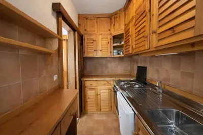a small kitchen with wooden cabinets and a sink at Ca La Casetta in Cortina dʼAmpezzo