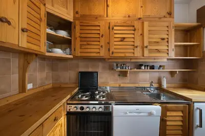 a kitchen with wooden cabinets and a stove top oven at Ca La Casetta in Cortina dʼAmpezzo