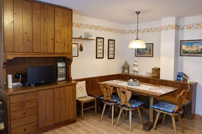 a kitchen with a table and chairs and a tv at Casa a Penia-Alba a 2 minuti da impianti funivia in Penia